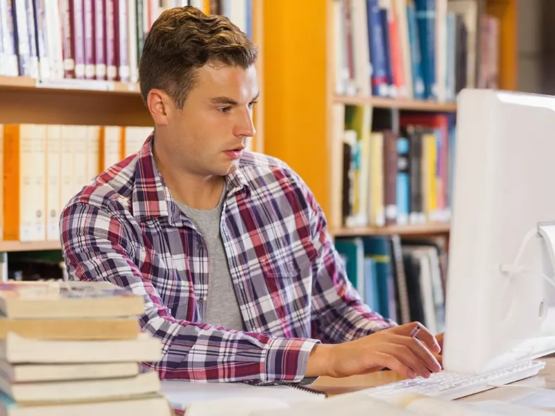 Focused student researching online math lessons on a library computer. Focused student researching online math lessons on a library computer.