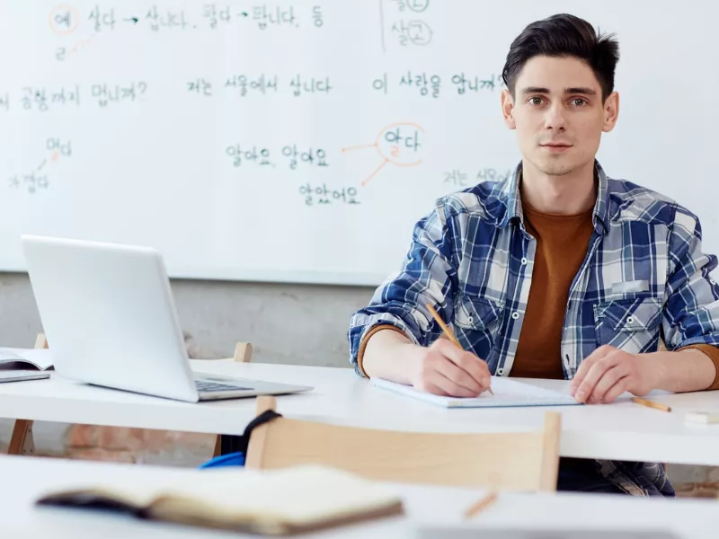 Student working at a classroom desk who needs MyMathLab homework help.